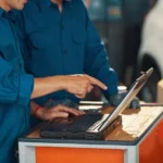 personas mirando ordenes de trabajo en el ordenador en un taller