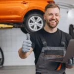 Hombre sonriendo en taller con portatil en la mano