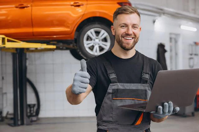 Hombre sonriendo en taller con portatil en la mano